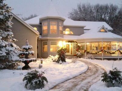 A snowy house with christmas lights on the porch