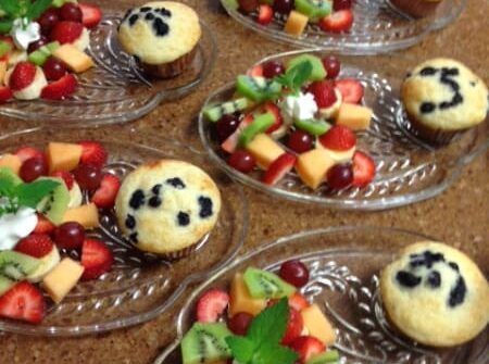 A bunch of plates of food with cupcakes and fruit on them