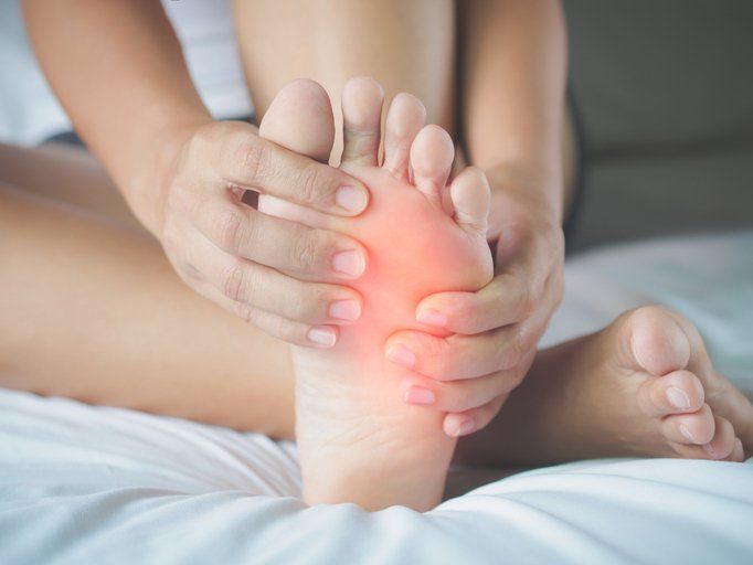 Closeup young woman feeling pain in her foot at home