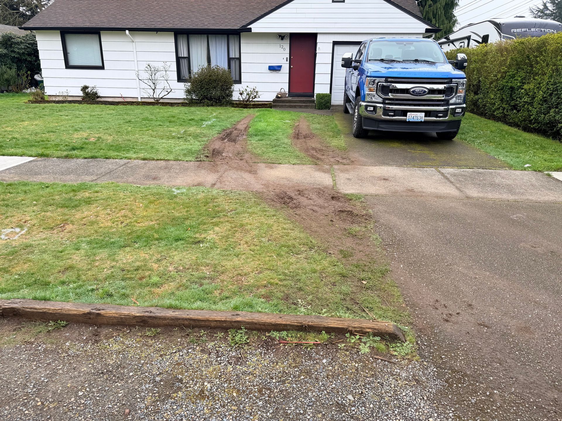 Single-story house with a red door, grassy yard, and blue pickup truck parked in the driveway.