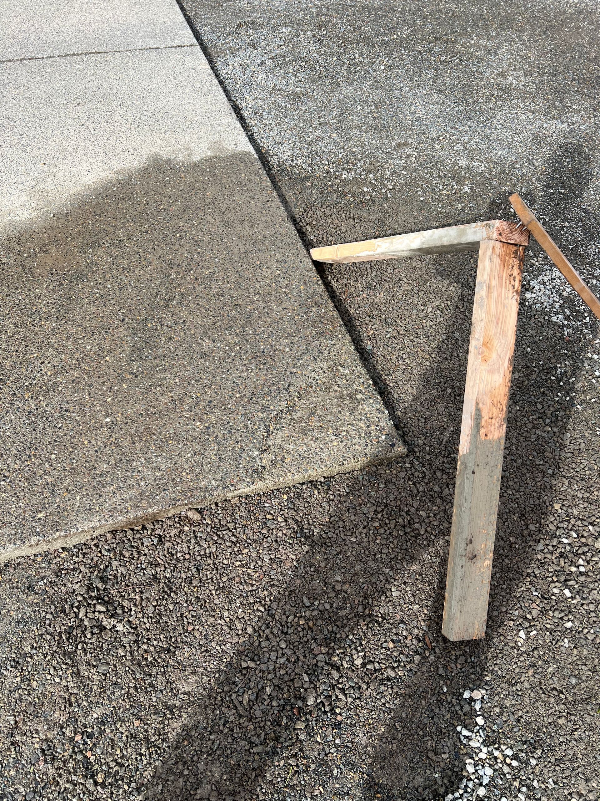 Broken wooden stake leaning on a gravel-roof surface with a dark shadow beside it