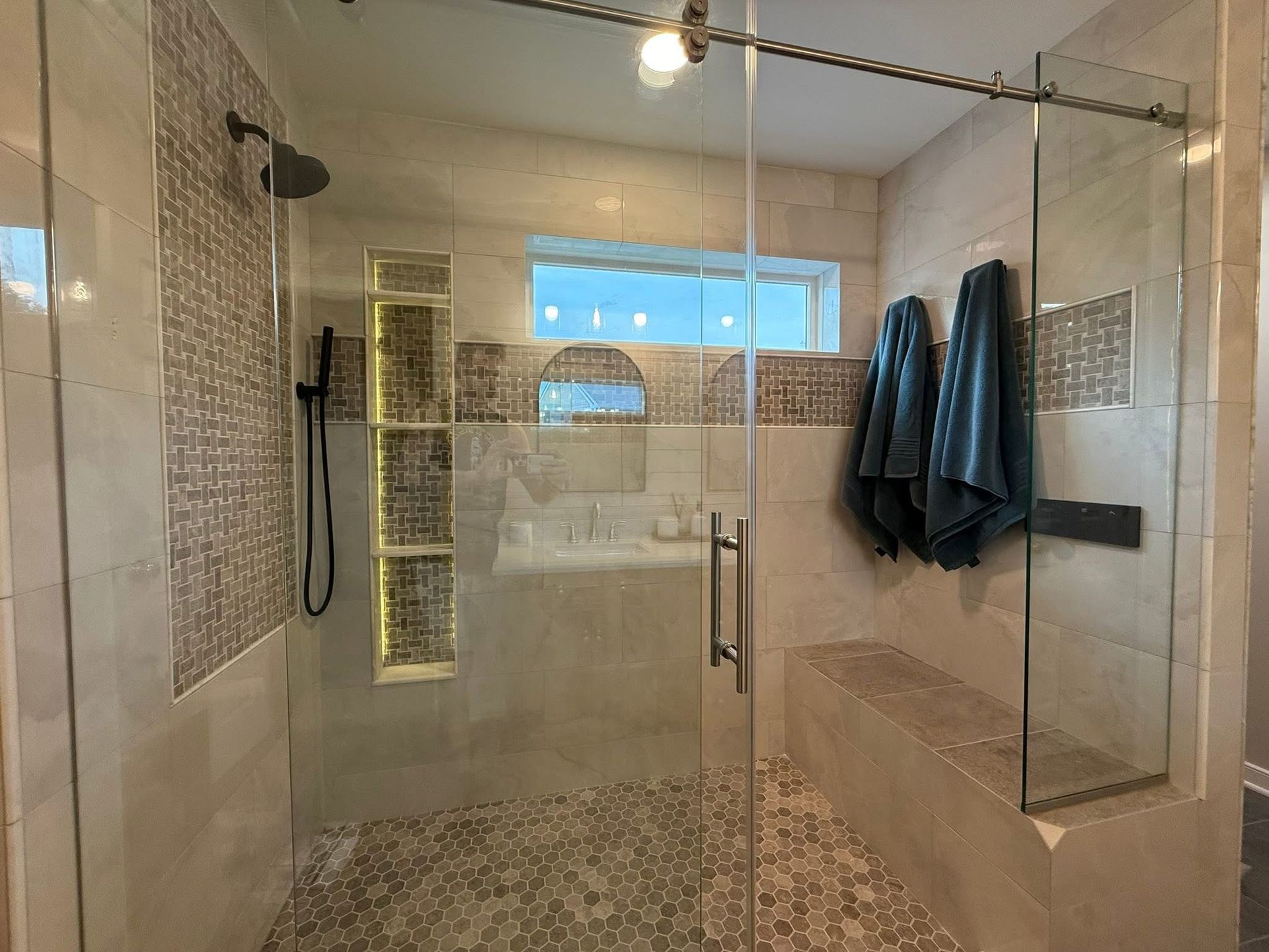 Worker installing a glass shower door in a bright bathroom