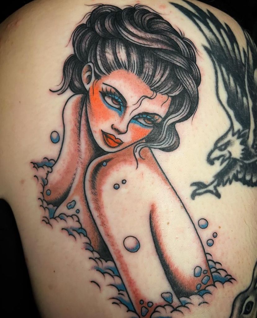 Stylized tattoo of a woman with dark hair, red accents, and bird silhouettes on a pale background