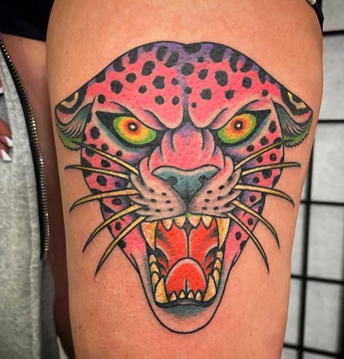 Colorful jaguar head tattoo with pink, green, and orange details on skin