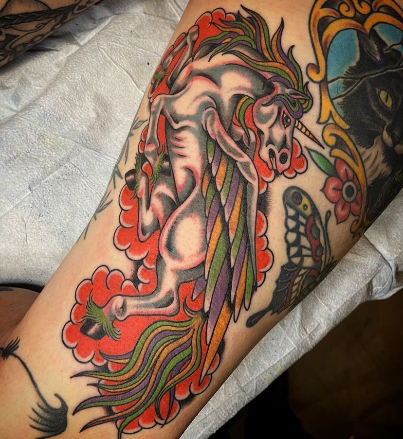 Colorful tattoo of a stylized elephant with flowing red, green, and black details on an arm