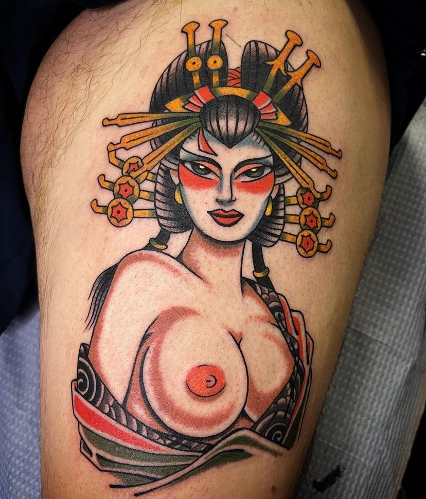 Stylized tattoo of a geisha with red makeup, black hair, and ornate gold hairpins on skin