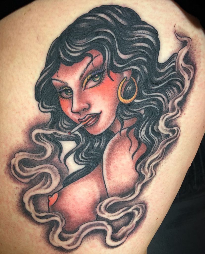 Stylized tattoo of a woman’s face with wavy black hair, red lips, and a gold hoop earring.
