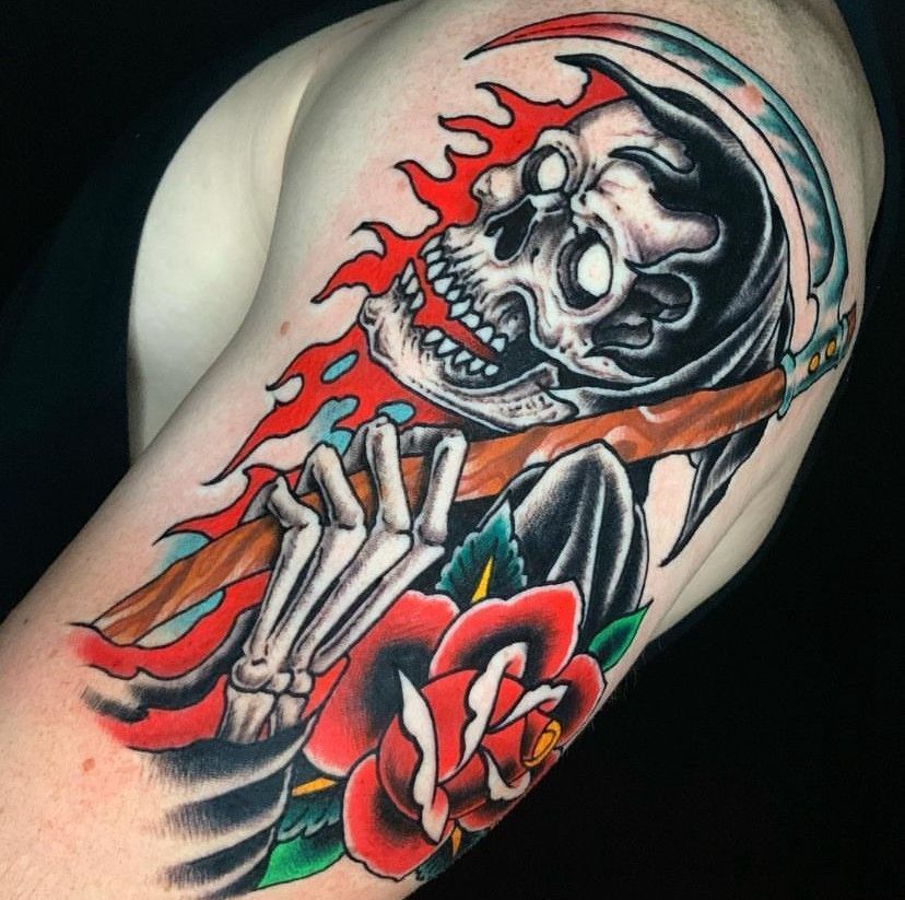 Colorful tattoo of a hooded skeleton with red flames and a red rose on skin