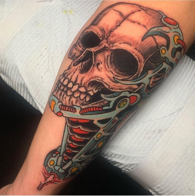 Colorful skull-and-snake tattoo on an arm, with red, black, and teal details