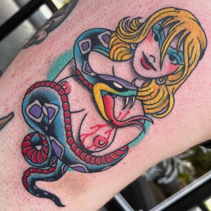Colorful snake and blonde cartoon woman tattoo on skin, with turquoise, yellow, red, and black details