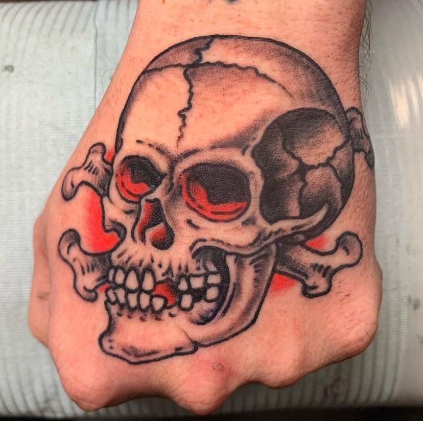 Black and red skull tattoo on the back of a hand