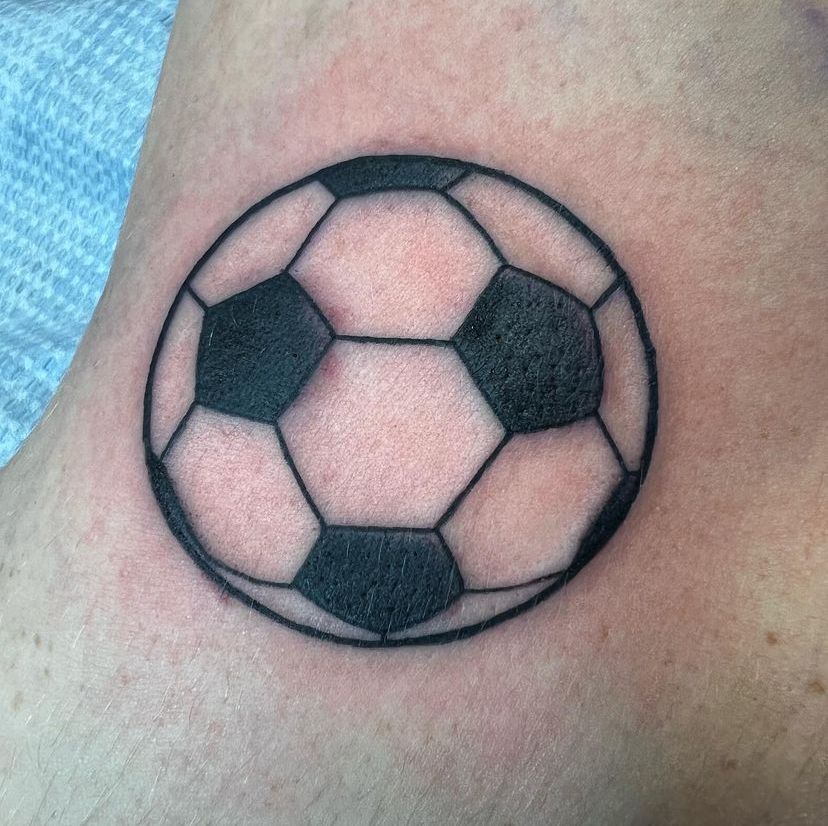 Small soccer ball tattoo with black and white panels on skin