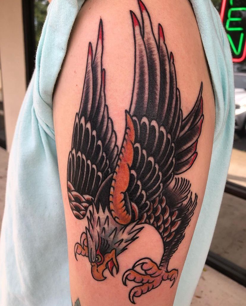 Black-and-orange eagle tattoo on a forearm, with wings spread and talons extended.