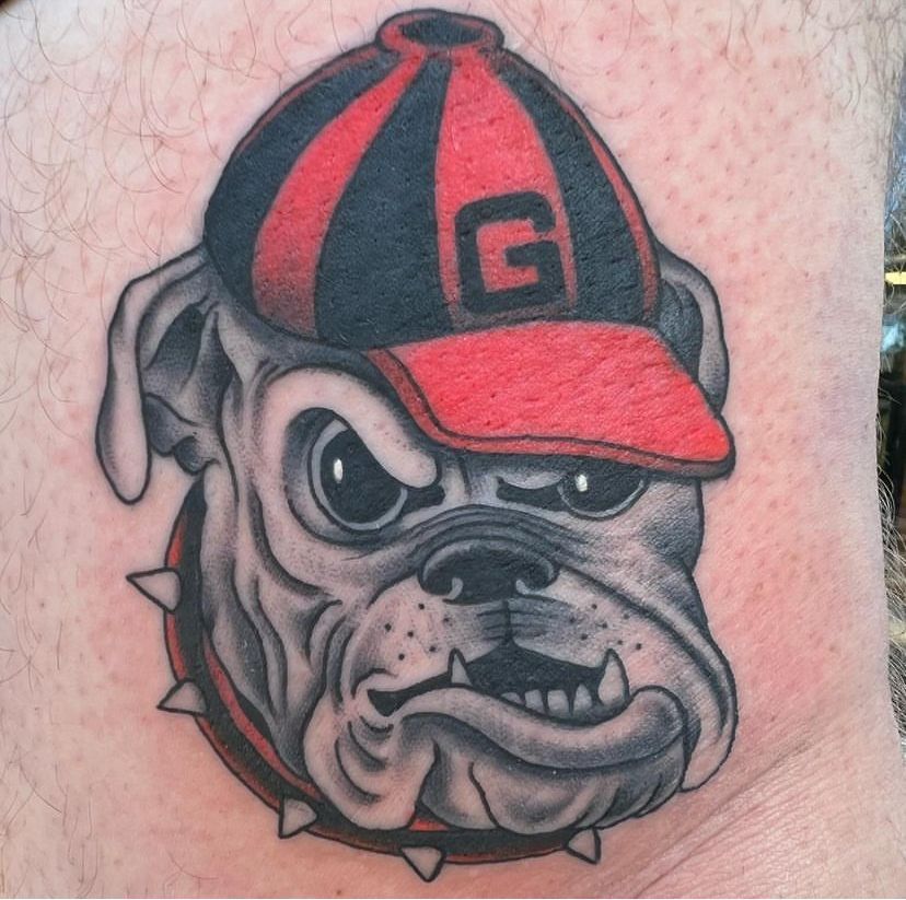 Bulldog tattoo wearing a red-and-black cap with a “G,” snarling expression