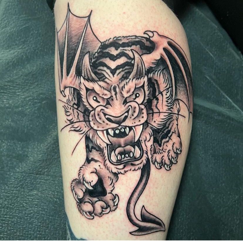 Black-and-gray tattoo of a snarling winged demon on a forearm