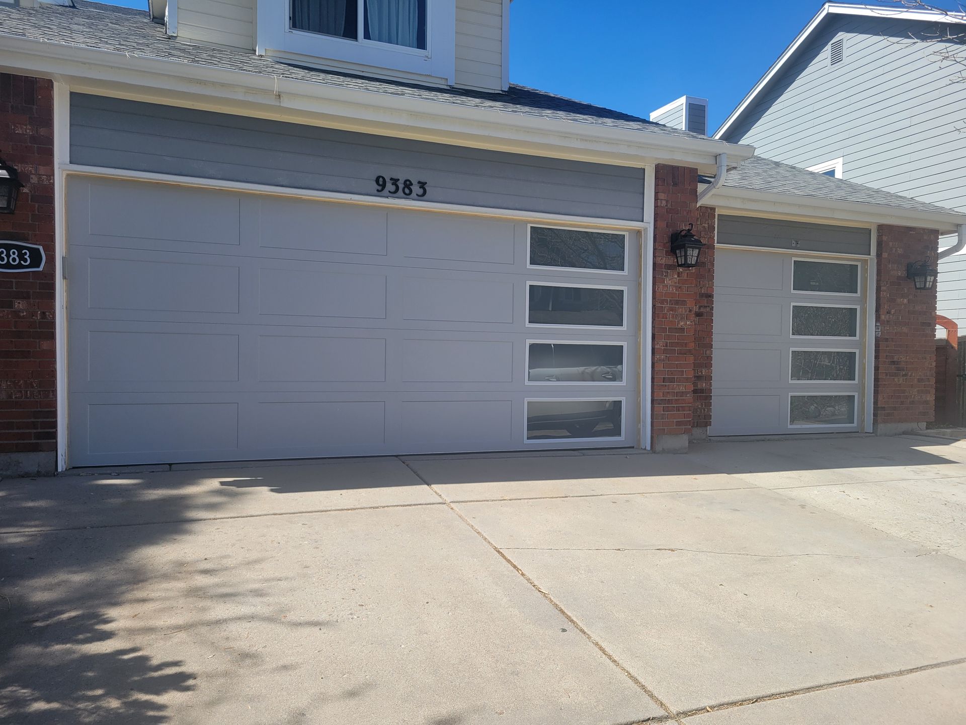 A residential house exterior featuring a wide two-car garage and a single-car garage with modern frosted-glass windows.