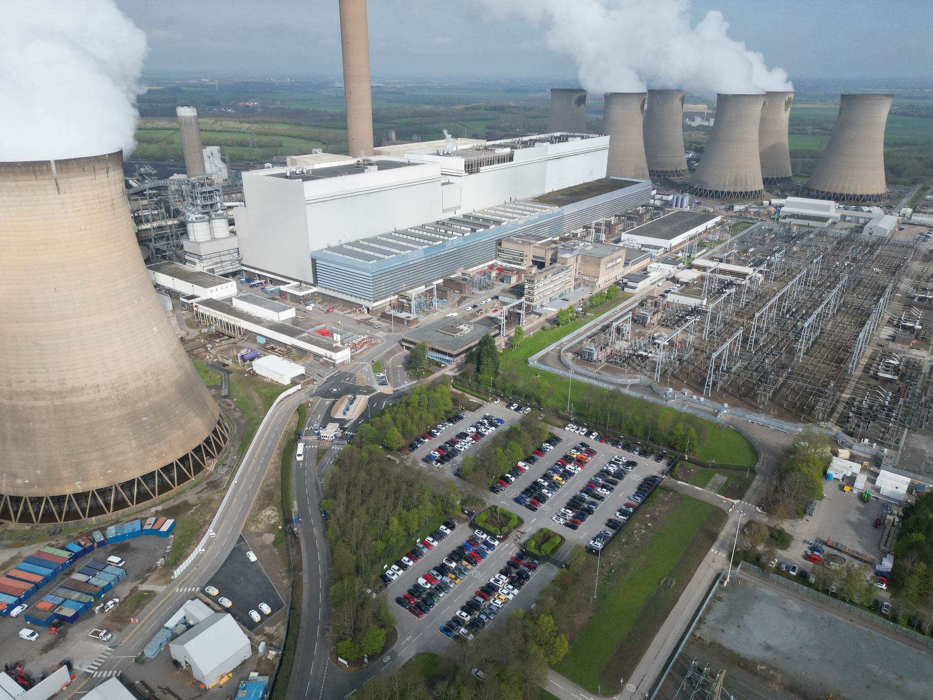 An aerial view of a power plant with smoke coming out of the cooling towers.