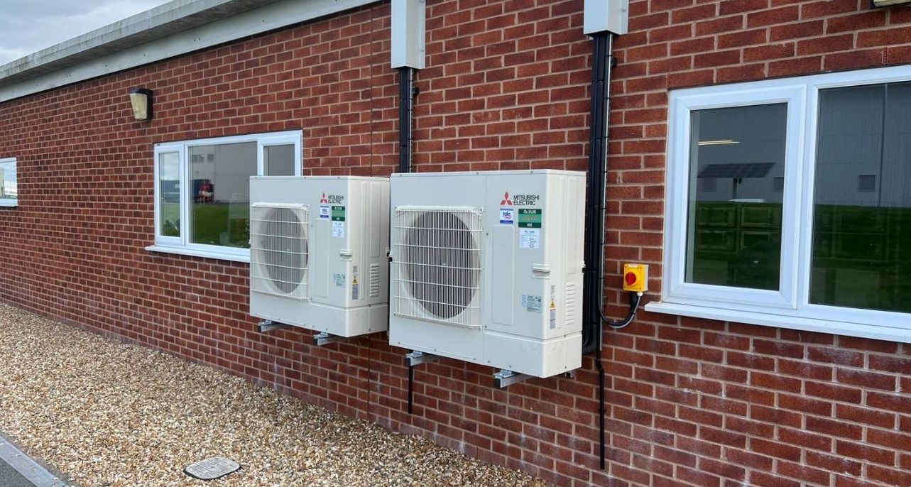 A row of air conditioners are sitting outside of a building.
