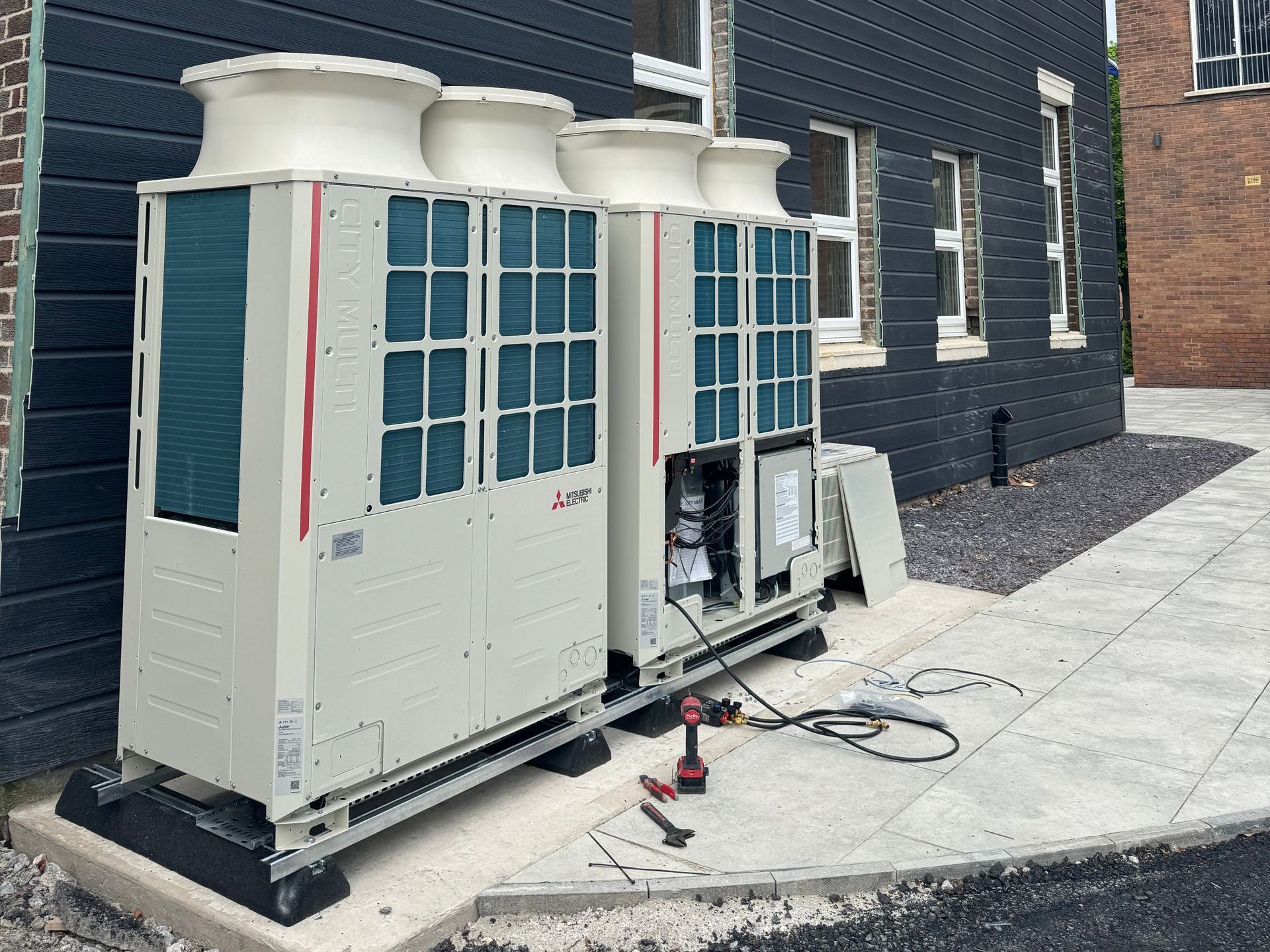 A man is working on an air conditioner on the roof of a building.