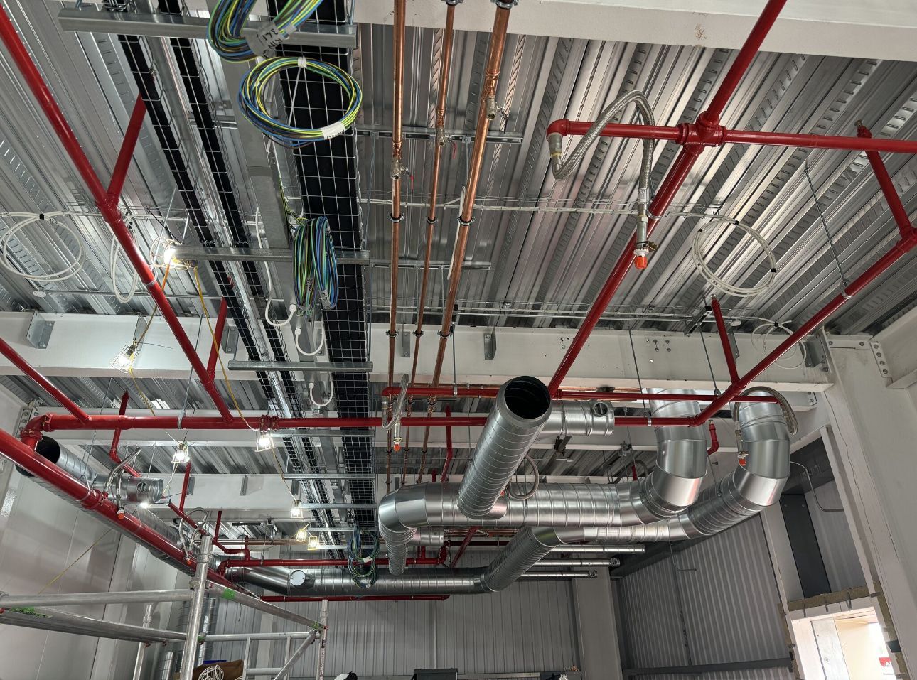 A bunch of pipes are hanging from the ceiling of a building.