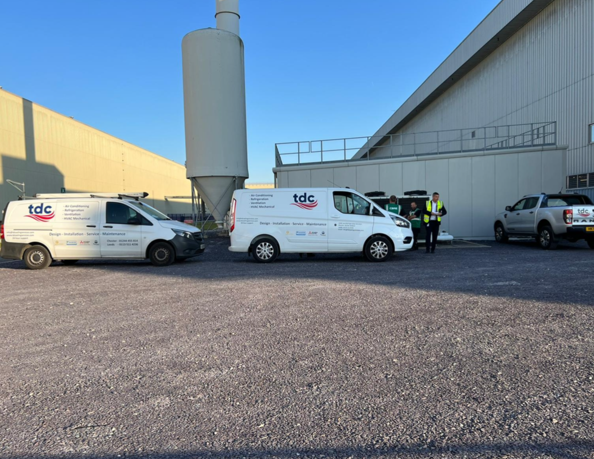 Two tdc vans are parked in front of a building