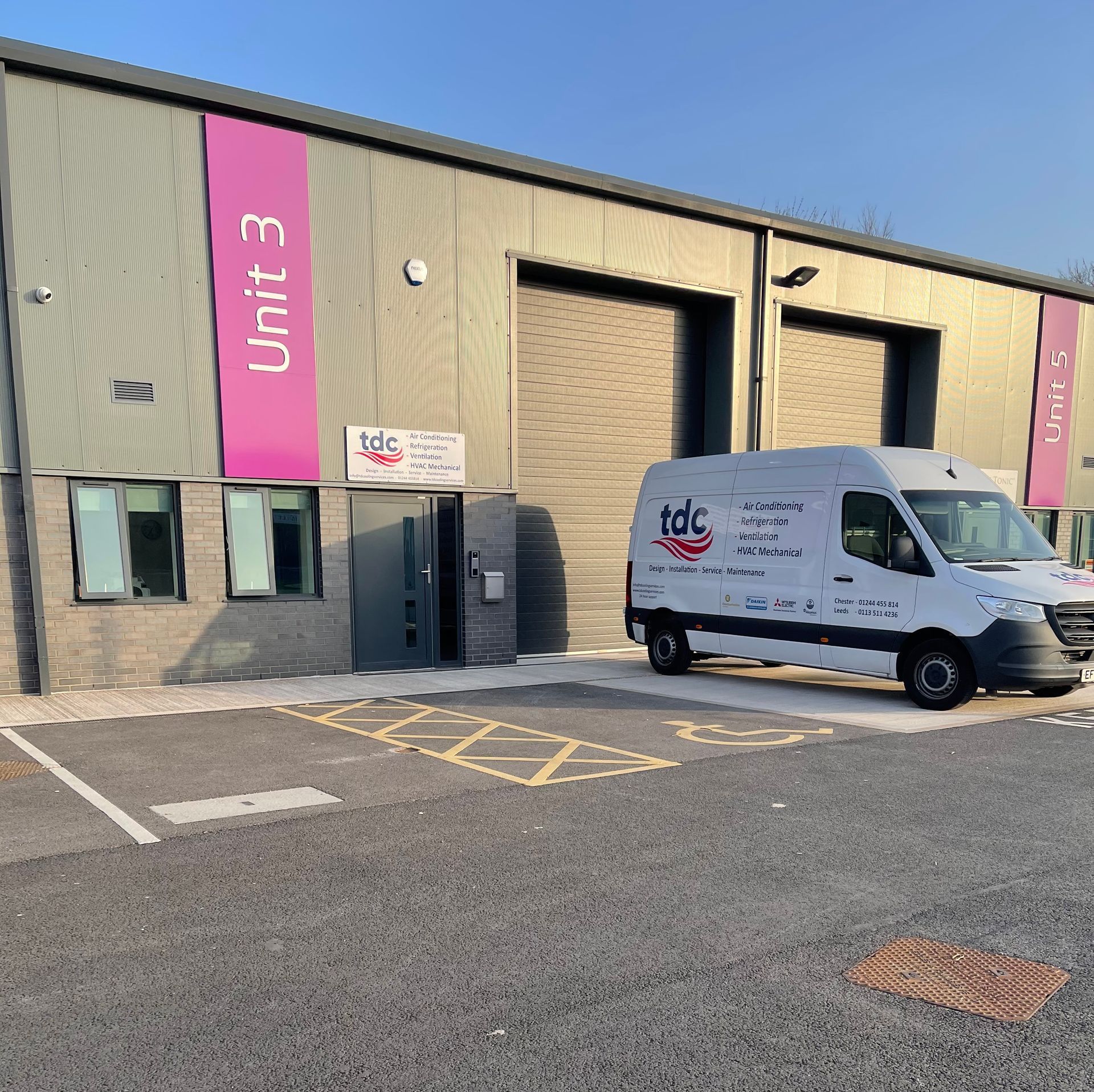 A white van is parked in front of a building that says unit 3