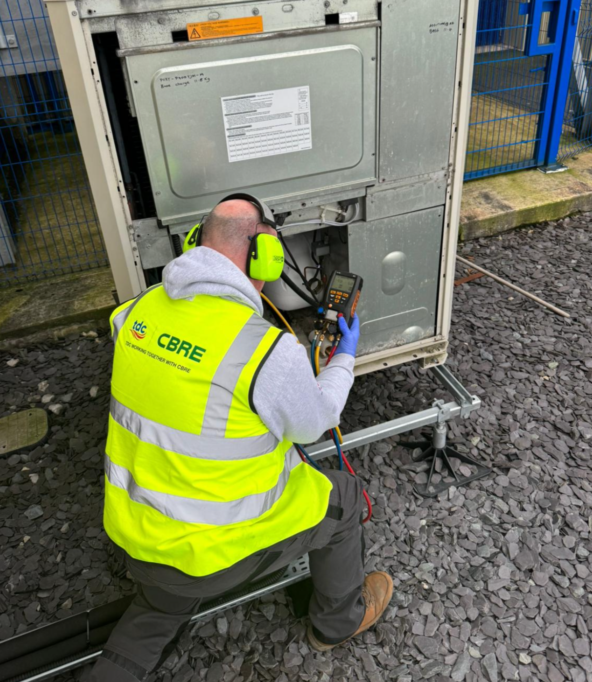 A man in a yellow vest is working on a machine.