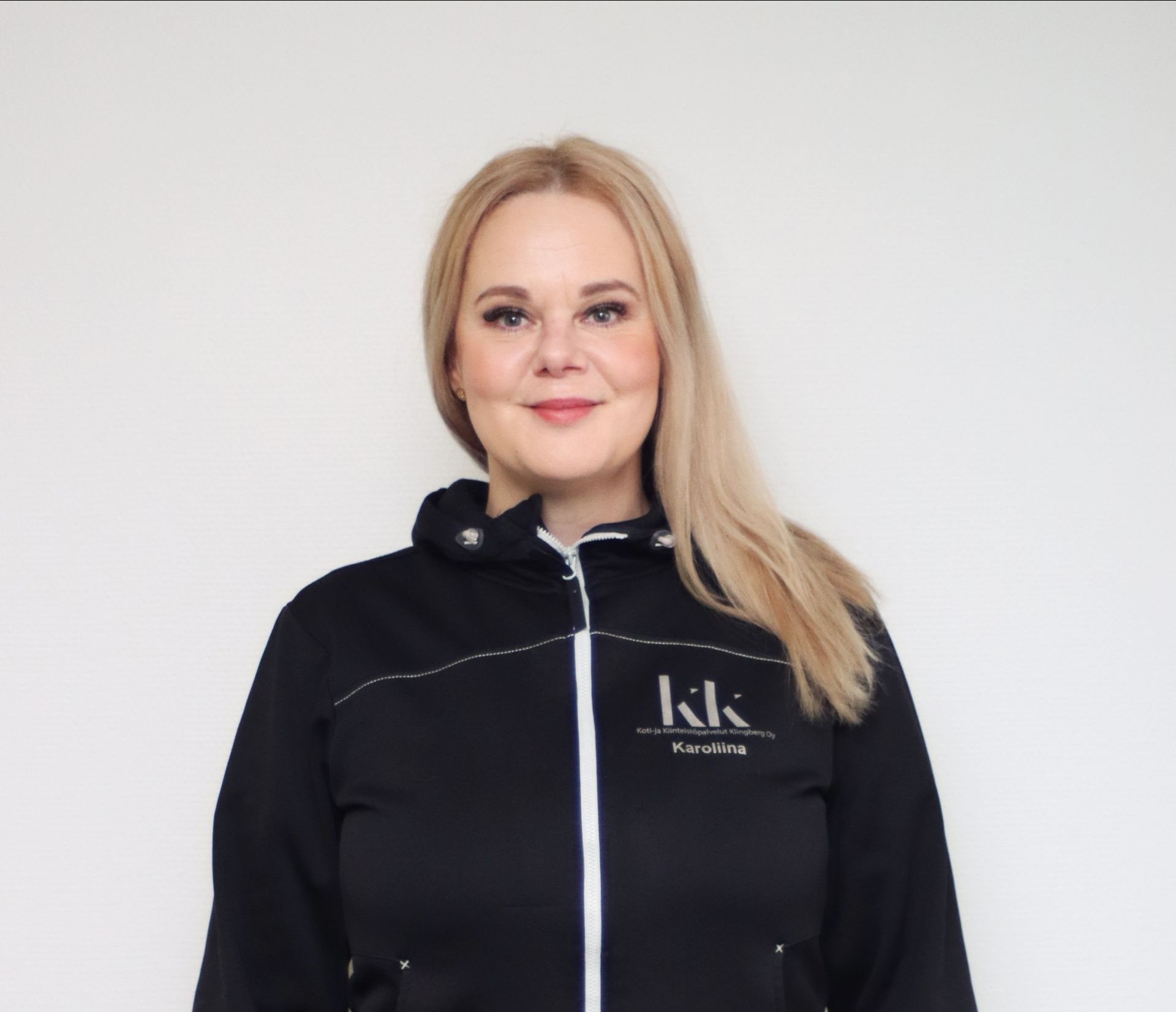 Nainen, jolla on yllään musta takki, jossa on sana kk