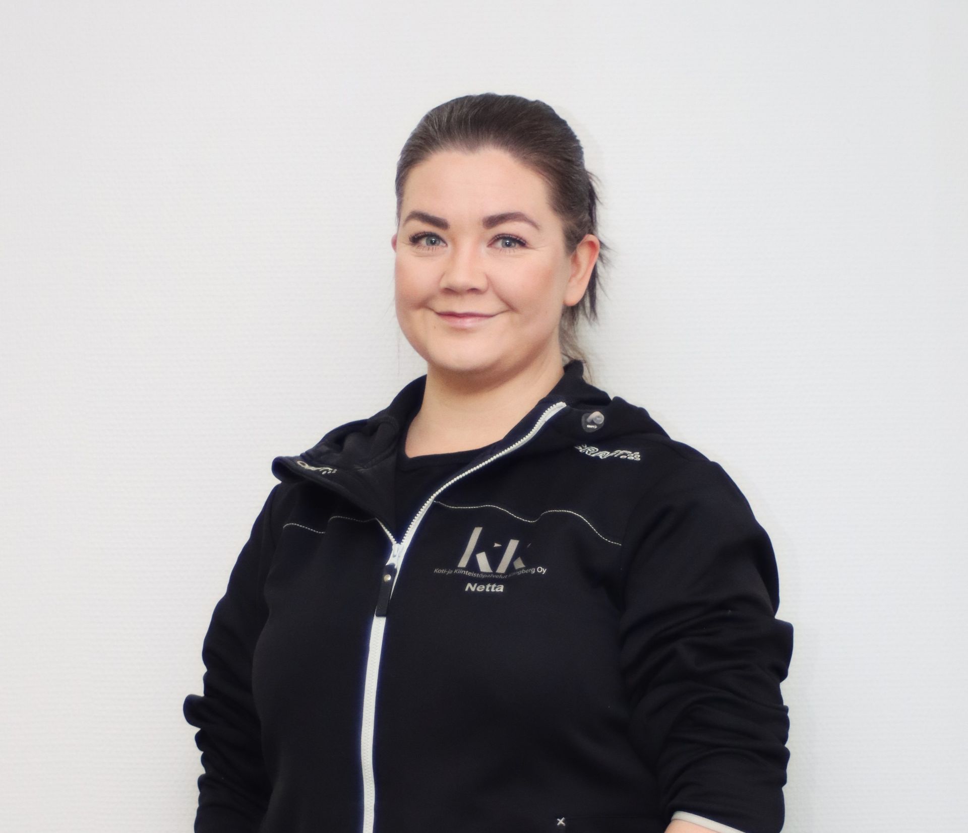 Nainen, jolla on yllään musta takki, jossa on k-kirjain