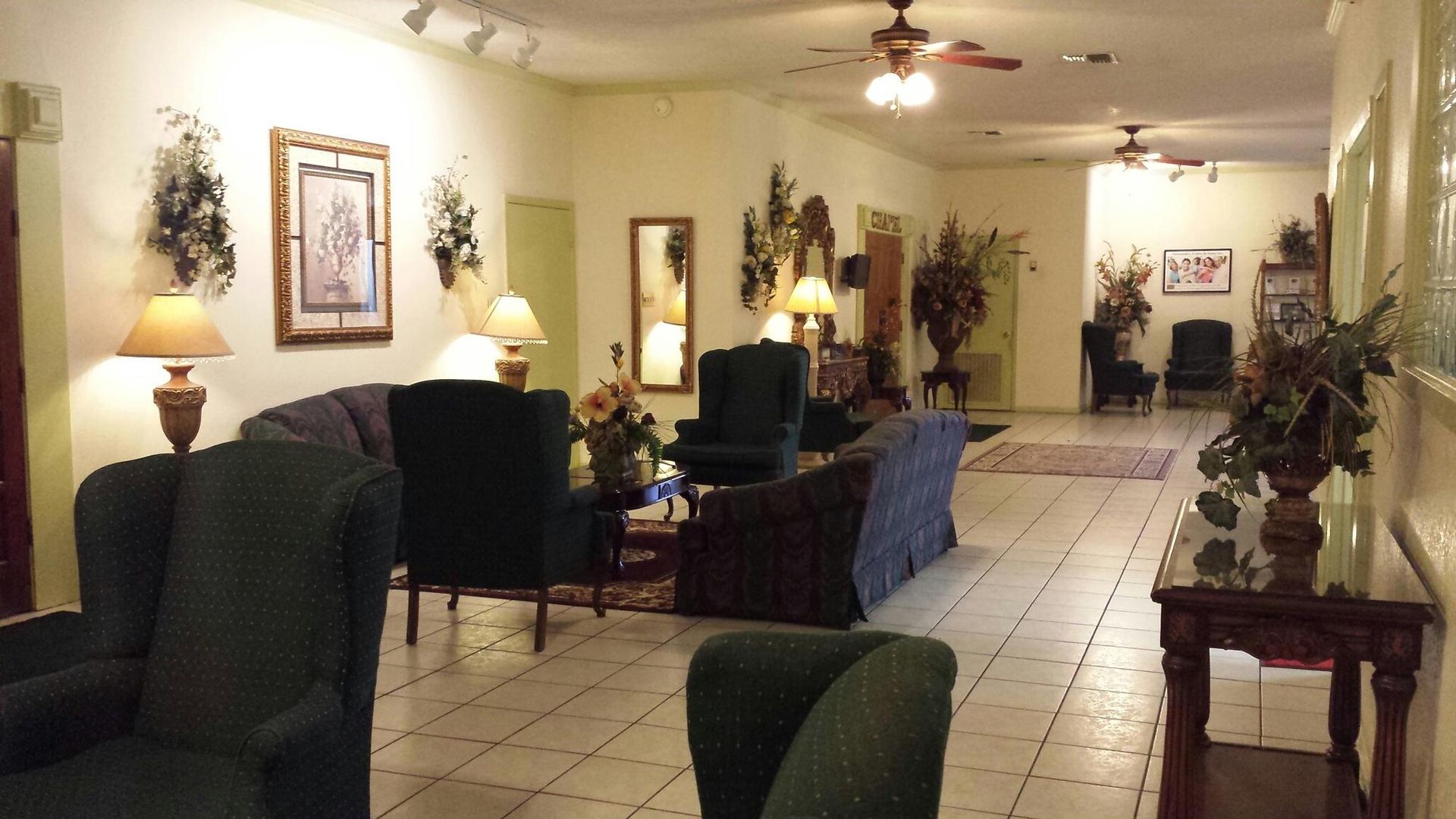 Spacious waiting room with seating, lamps, artwork, and ceiling fans.