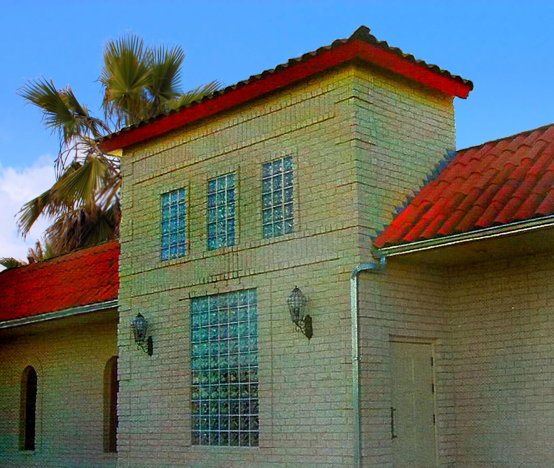 Brick building with red tiled roof and glass block windows against a blue sky.