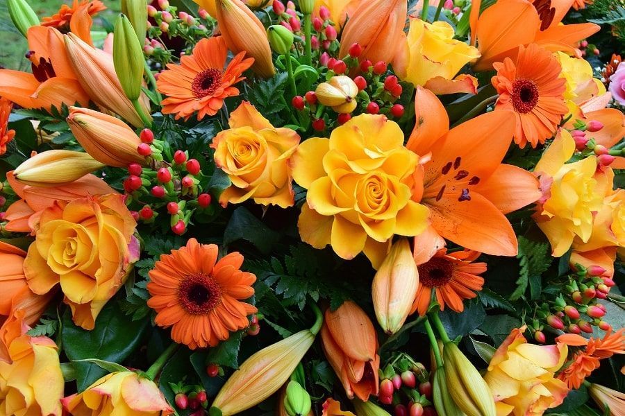 People arranging flowers on a wooden table, hands visible, with bouquets of various colors.