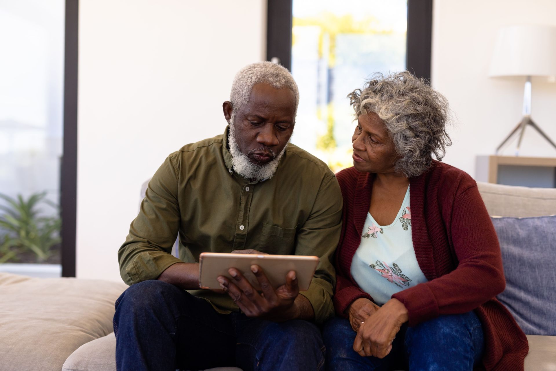 Two people sitting on a couch looking at a tablet together
