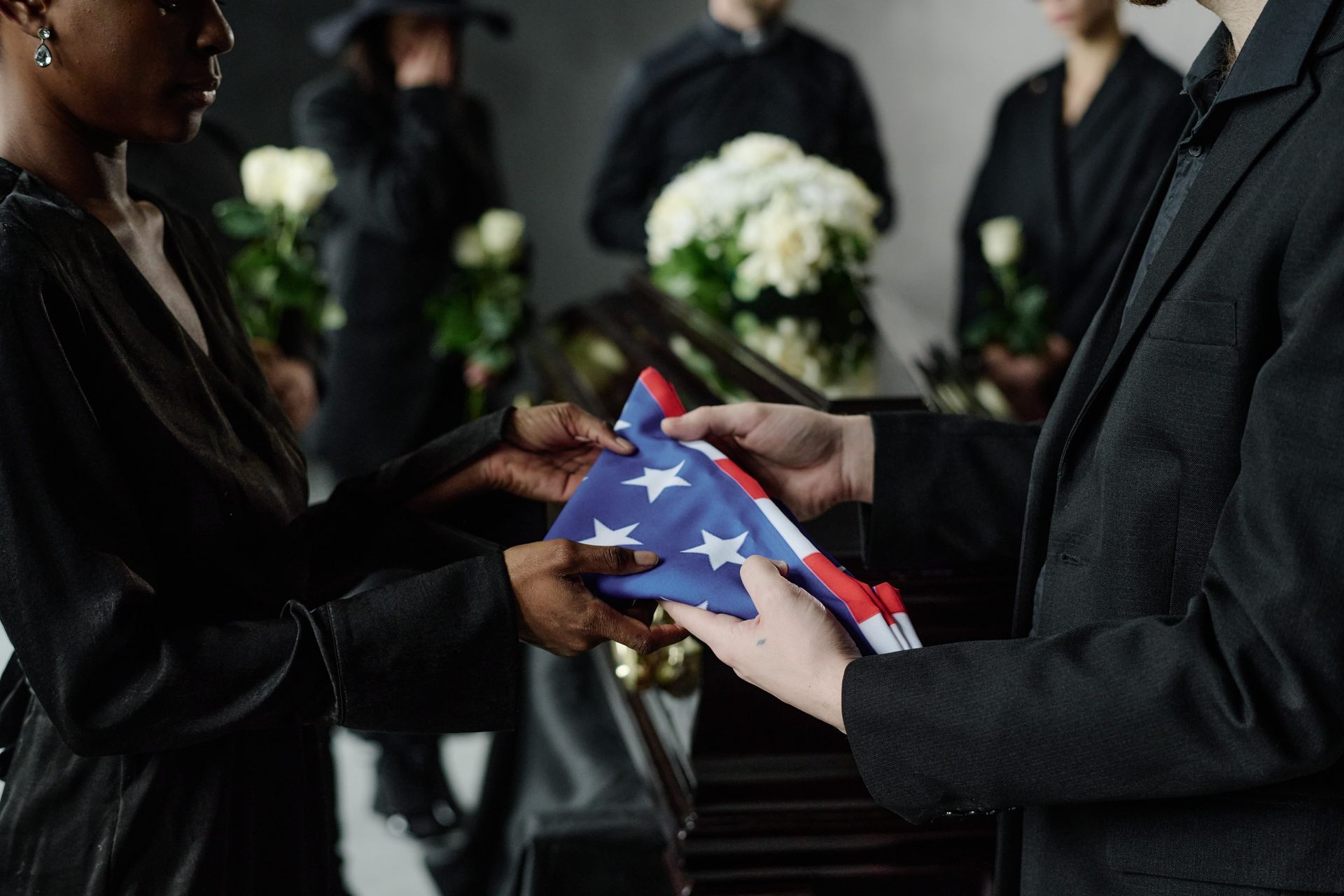 A group of people are standing around a coffin at a funeral.