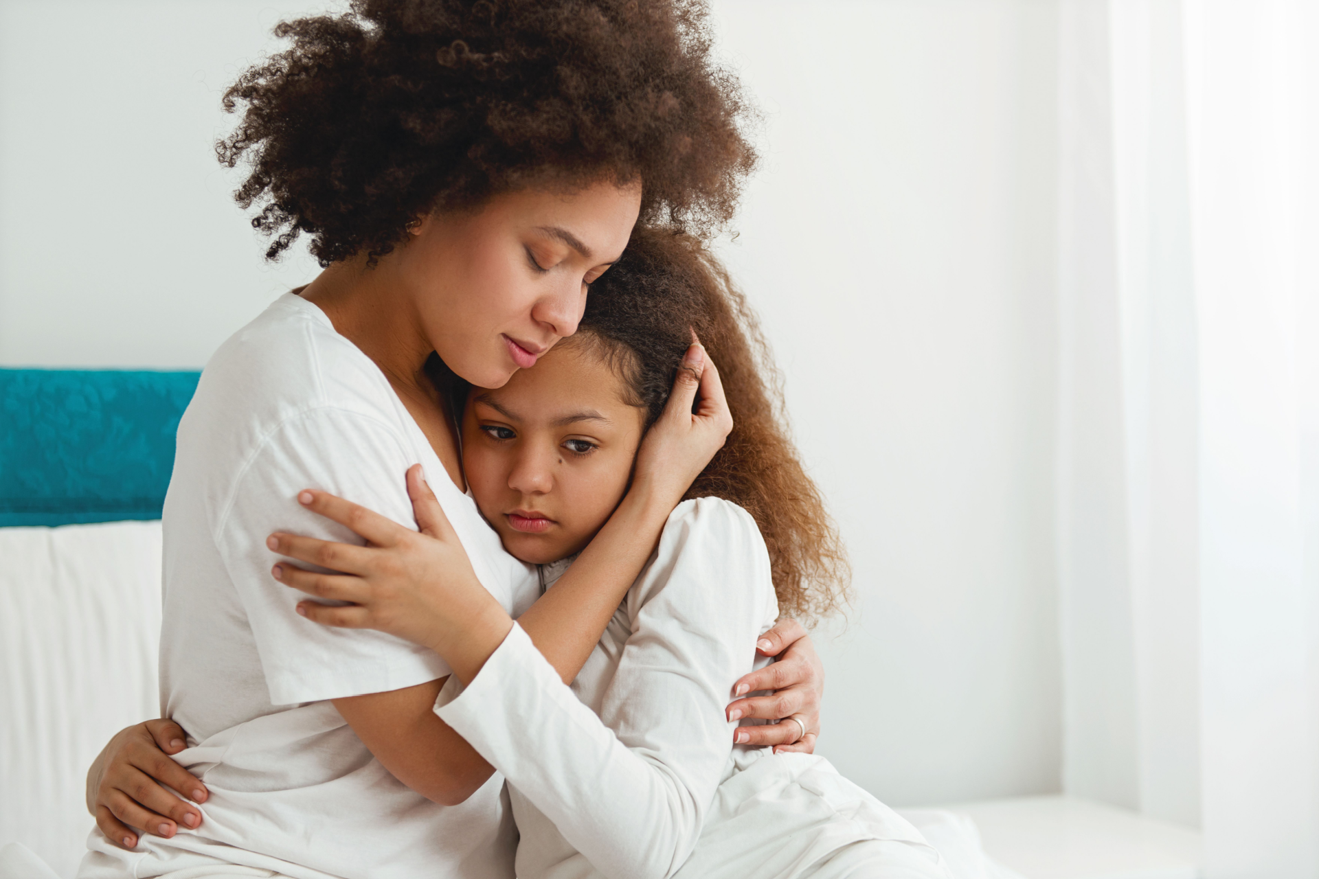 A woman is sitting on a couch talking to a little girl.
