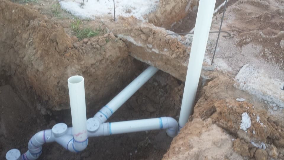 A bunch of pipes are sitting in the dirt in a hole.