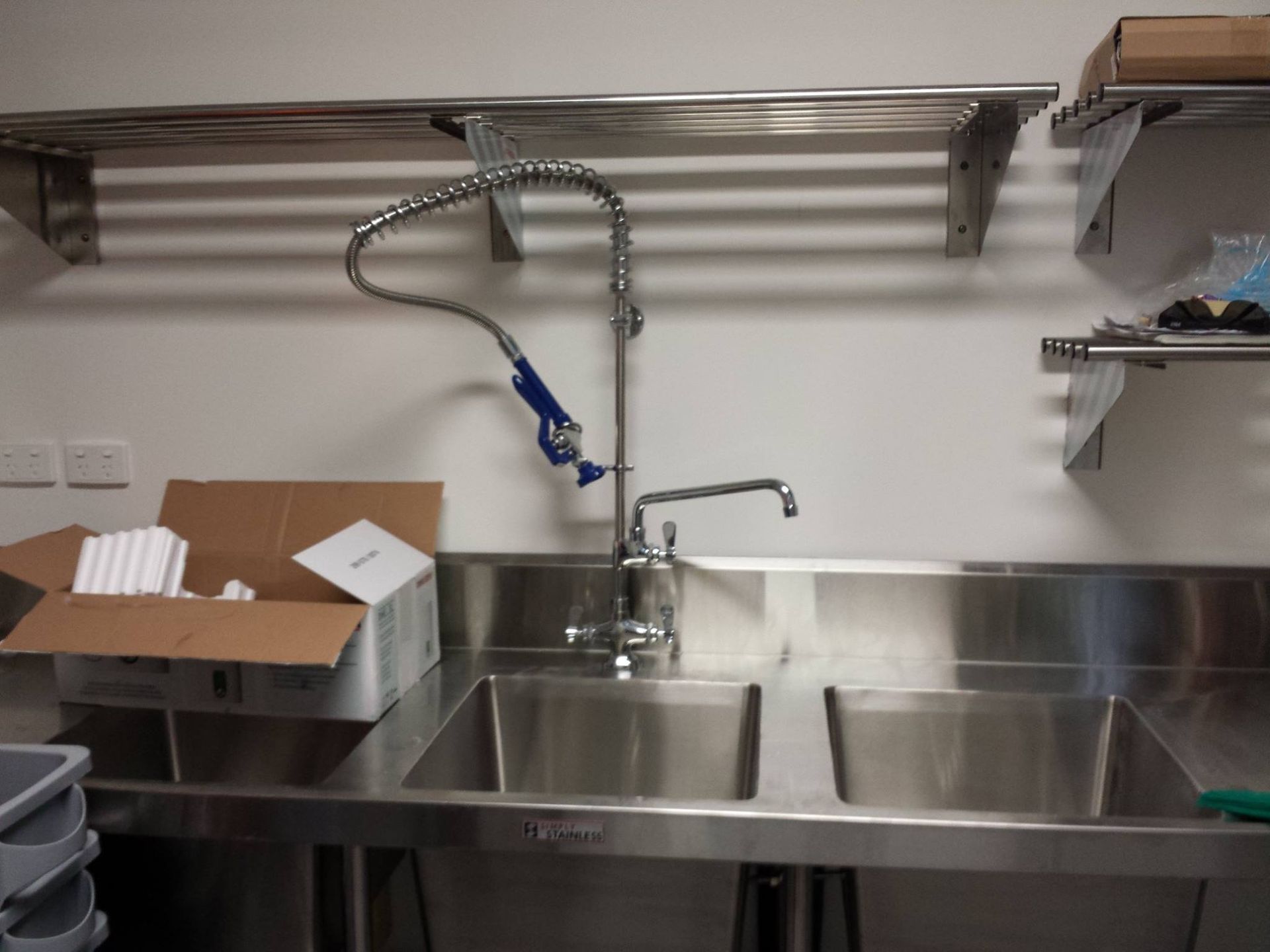 A plumber repairing pipes under a sink in a residential kitchen.