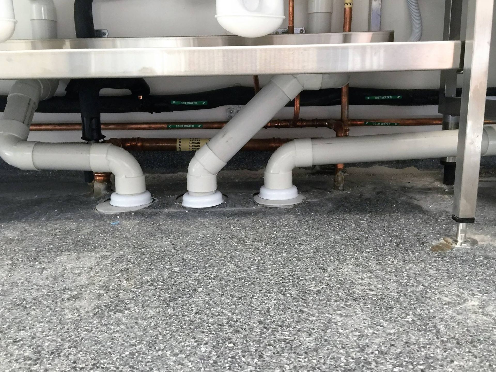 A stainless steel sink with a lot of pipes underneath it