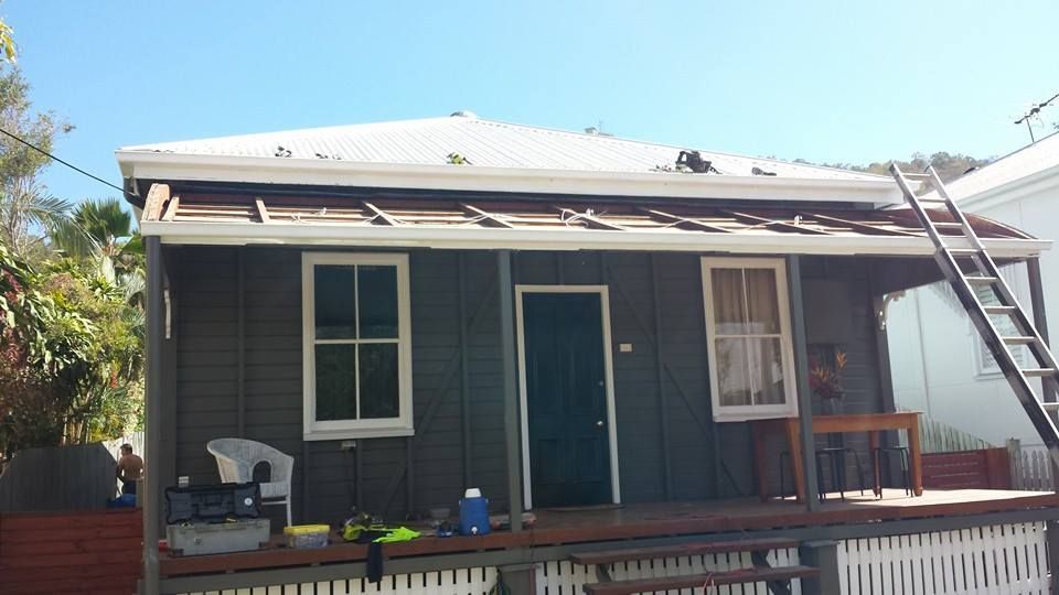A small house with a white roof and a ladder on the porch.