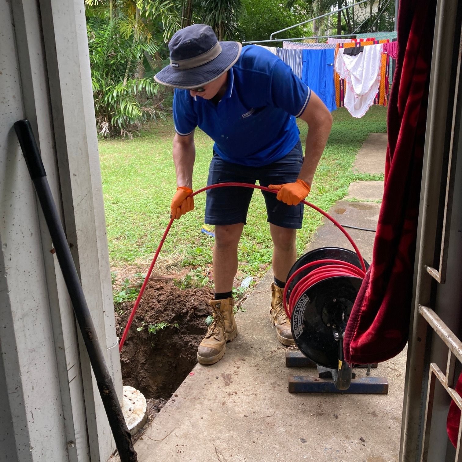 A man wearing a hat and gloves is working on a pipe