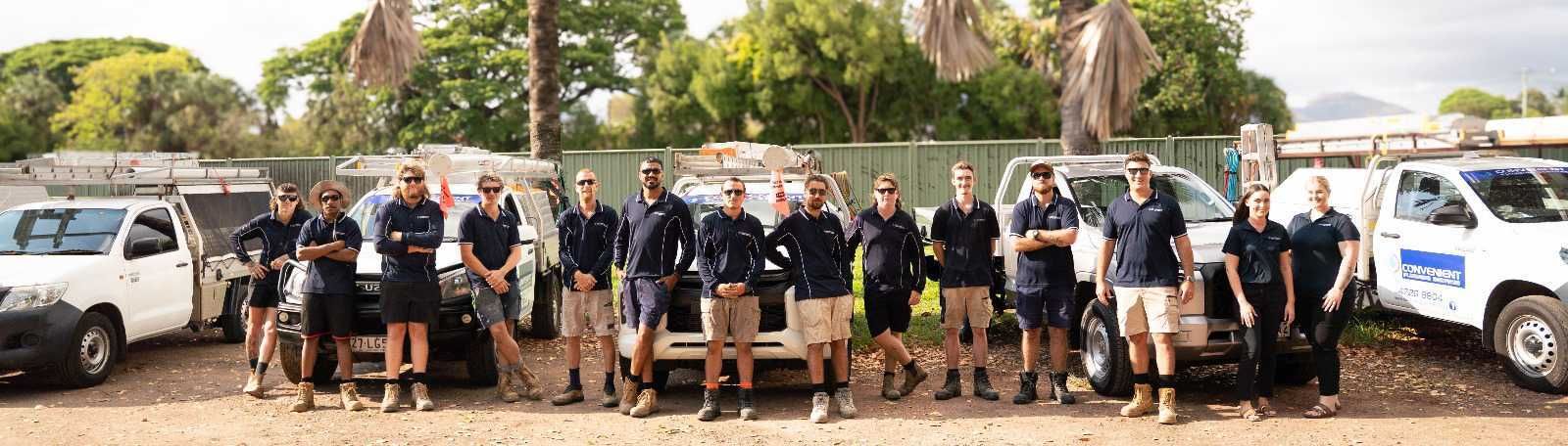 A group of people standing in front of white trucks, they are wearing dark blue shirts