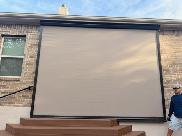 Large beige retractable screen mounted between brick walls above a raised wooden deck