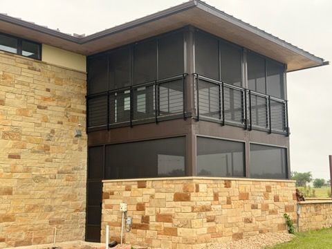Modern two-story building with stone walls and a screened upper balcony