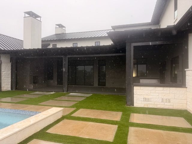 Modern house courtyard with grass, stone pavers, and a pool under a covered patio