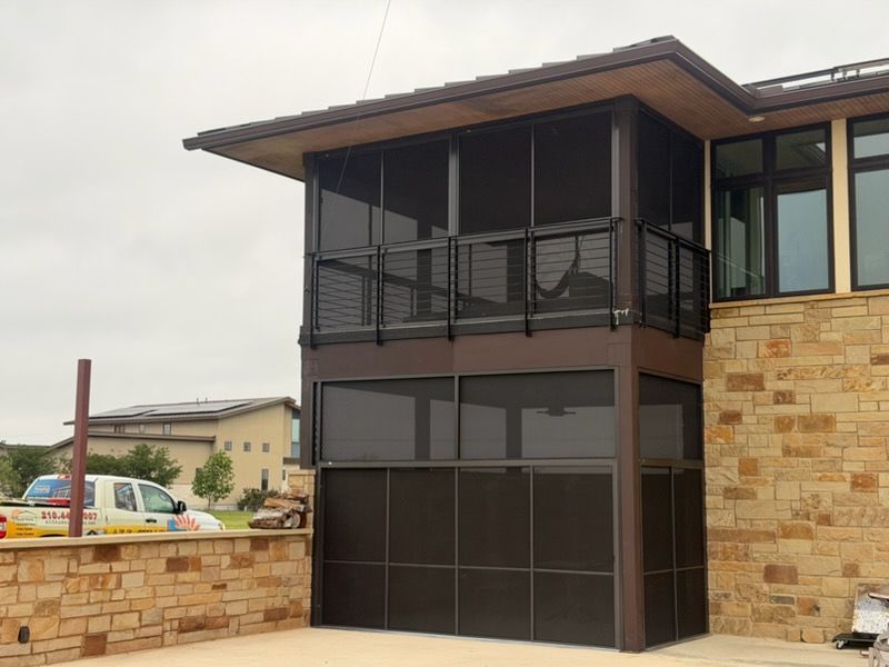 Modern two-story house with dark wood and stone exterior, balcony, and large windows