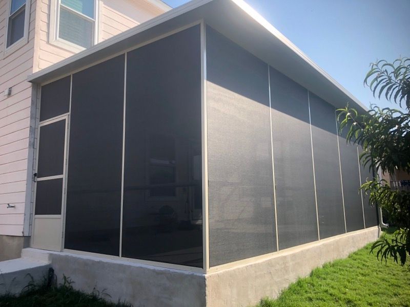 A screened in porch in the backyard of a house.