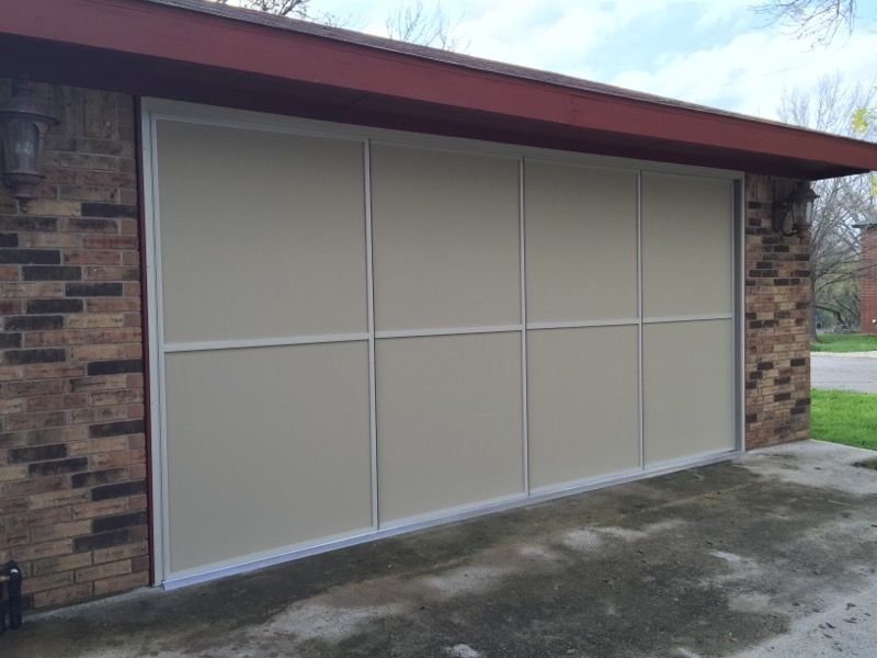 A white garage door is sitting on the side of a brick building.