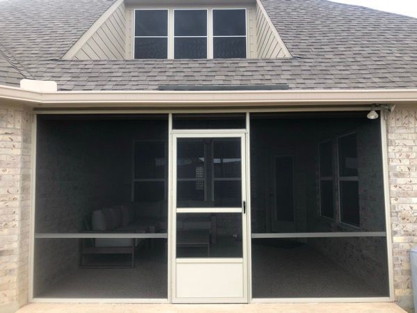 A screened in porch with a brick building in the background.