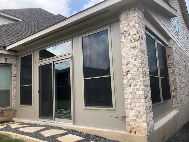 A house with a screened in porch and sliding glass doors.
