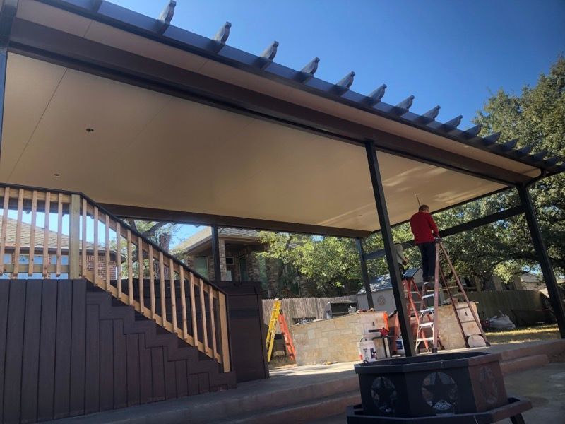 A man is standing on a ladder under a covered porch.